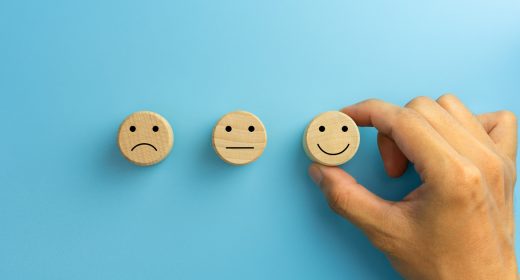 Customer service evaluation and satisfaction survey concepts. The client's hand picked the happy face smile face icon on wooden cube on blue background. copy space